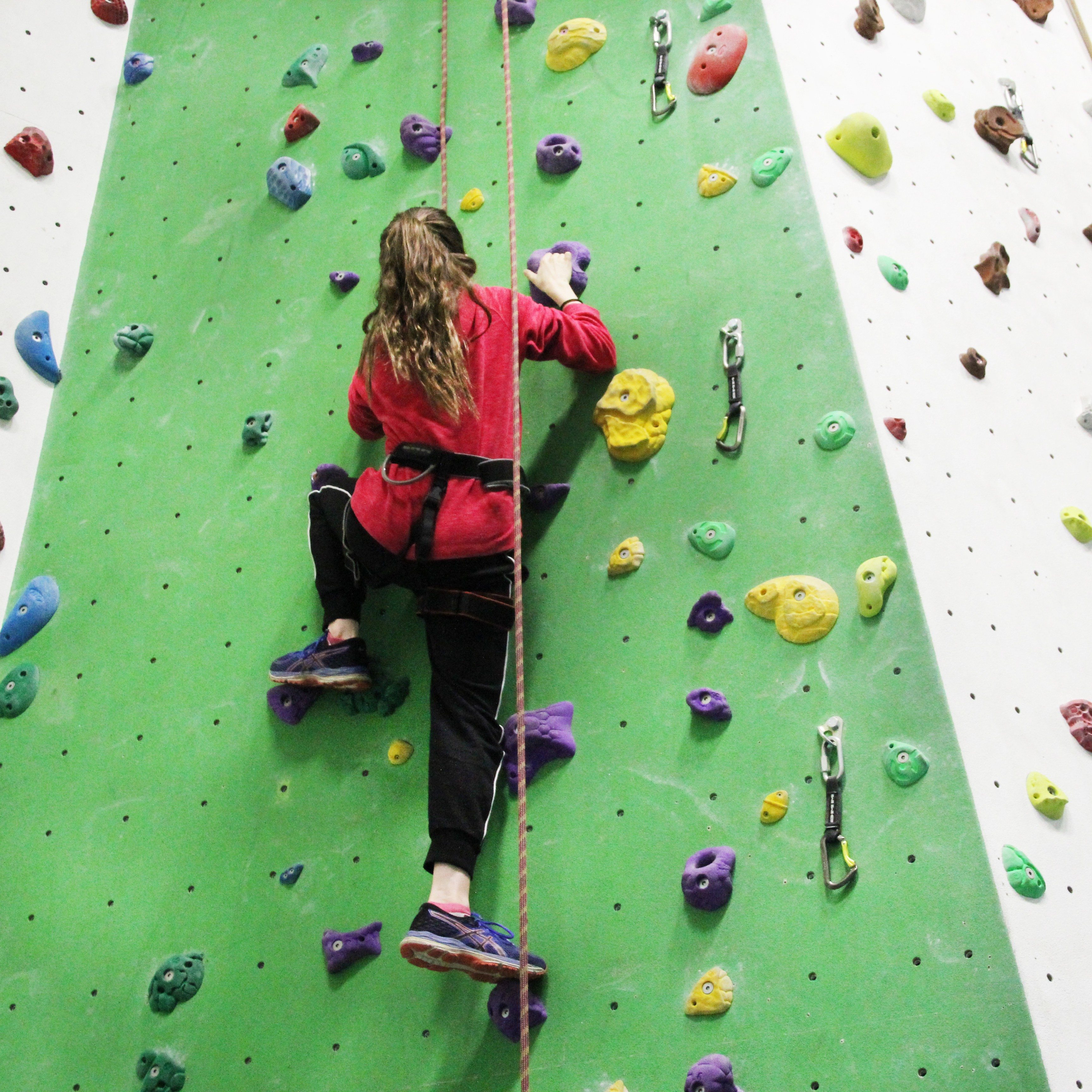 Young person using indoor top rope climbing wall